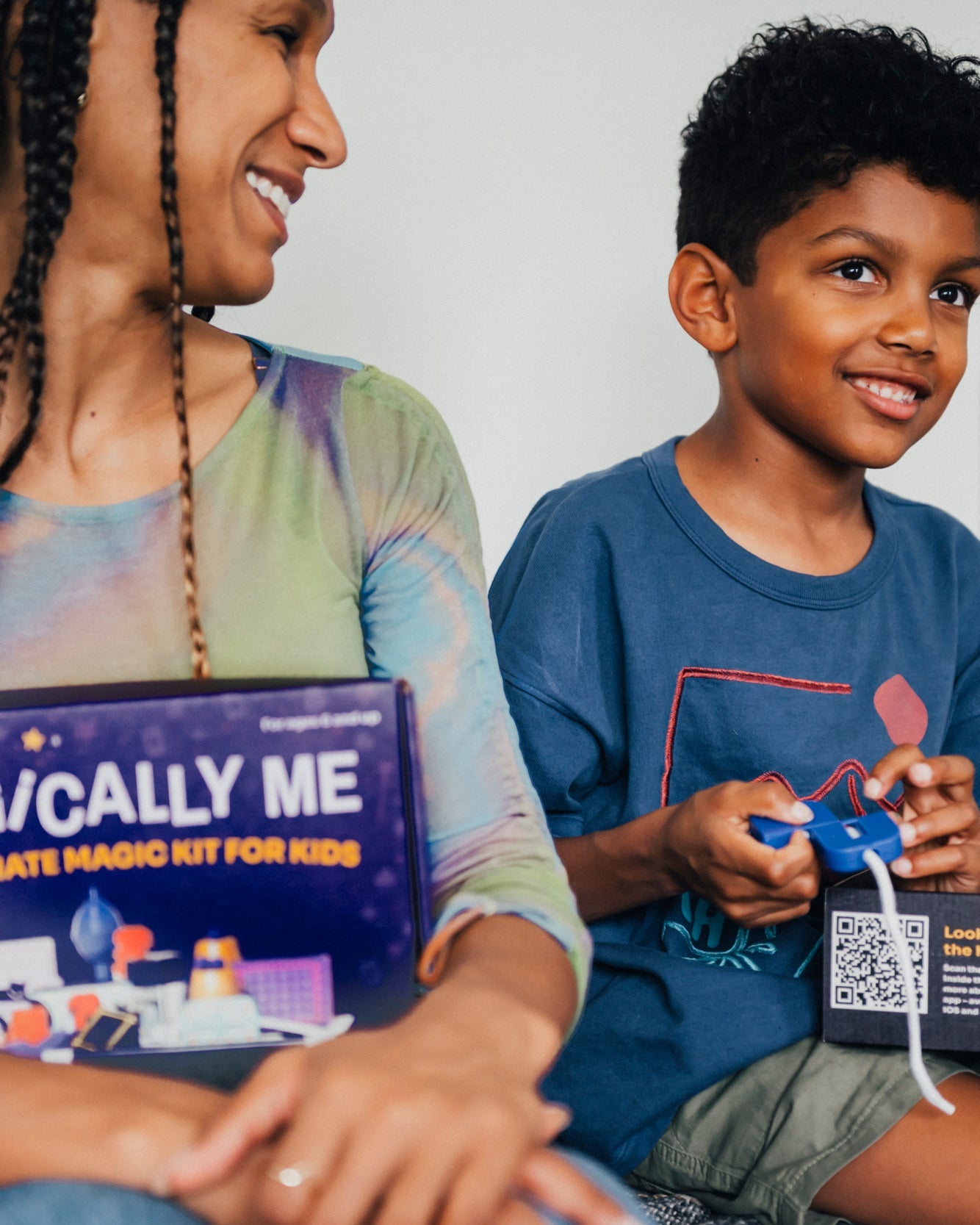 Magician Nicole Cardoza sitting with a young magician, holding the open Magically Me Kids Magic Kit box, both laughing—showcasing inclusive magic props and SEL learning features.
